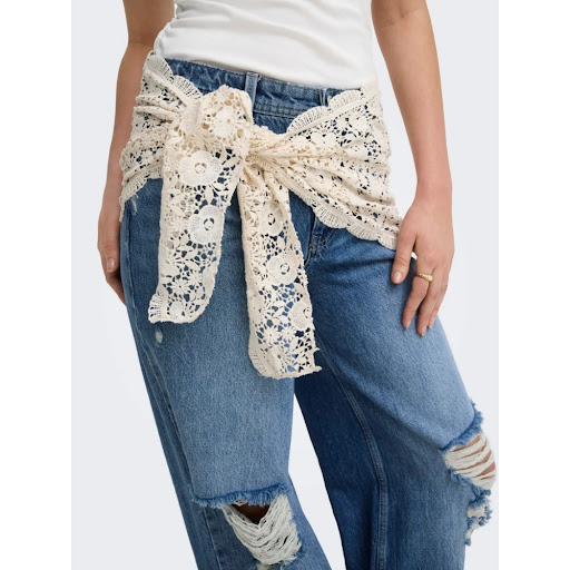 Product photo of ripped blue jeans worn with a white lace belt tied in a bow